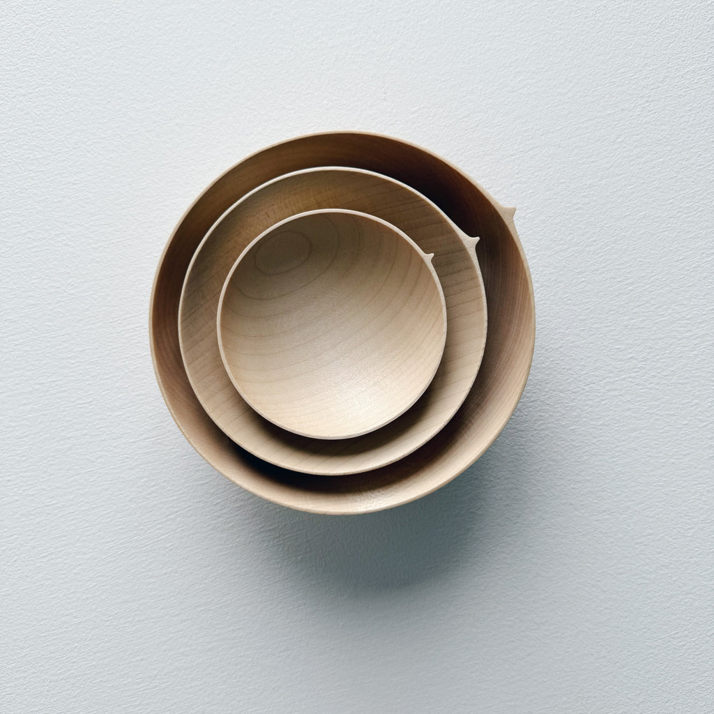 Three sycamore wooden bowls, stacked in a nesting formation on a white surface.
