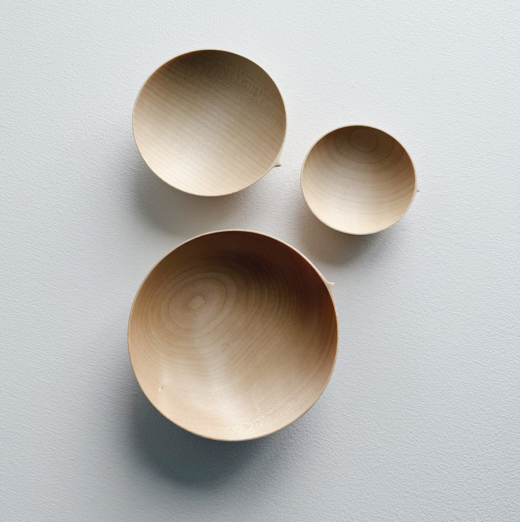 Three sycamore wooden bowls on a white surface