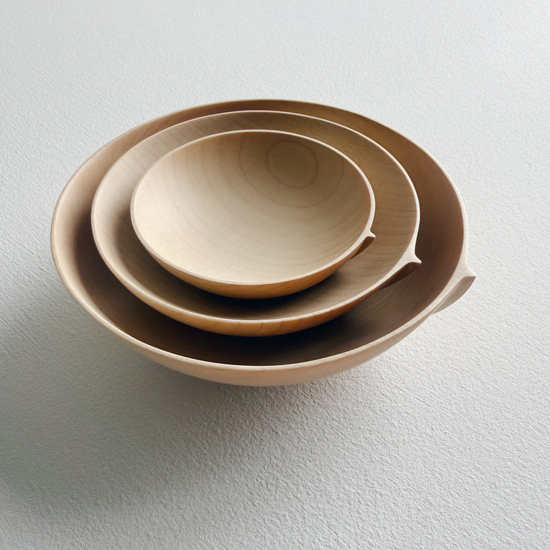 Three sycamore wooden bowls, stacked in nesting formation on a white surface