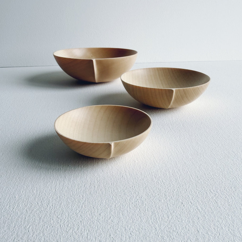 Three sycamore wooden bowls on a white surface